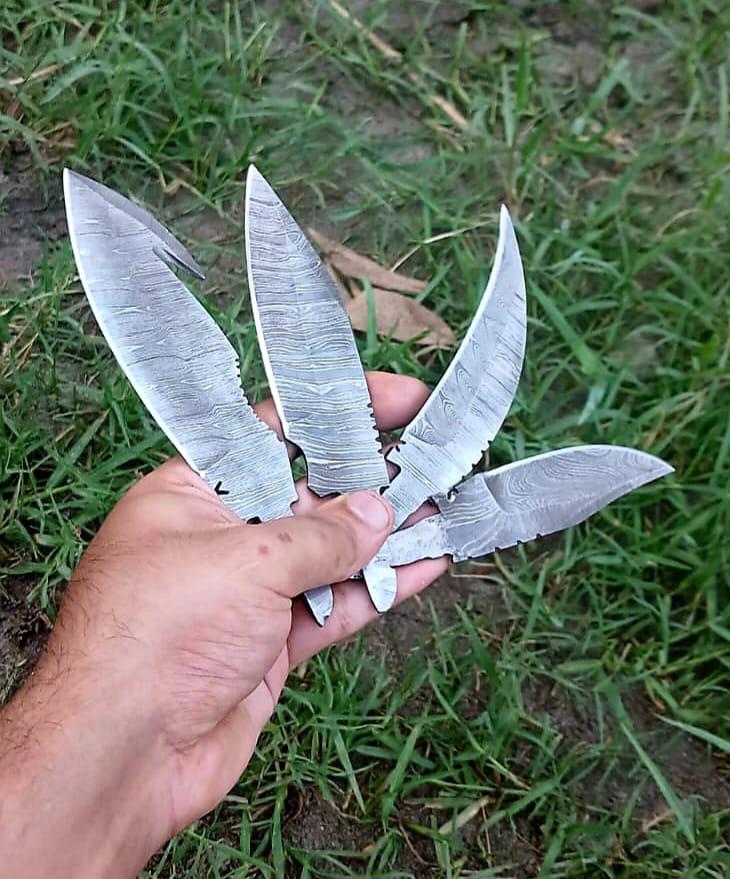 Hand holding four damascus blades with a gut hook, a leaf, a recurve, and a drop point.