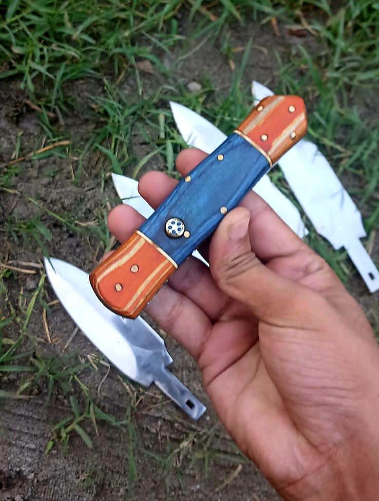 Blue and amber handle held above three bright blades on the ground.